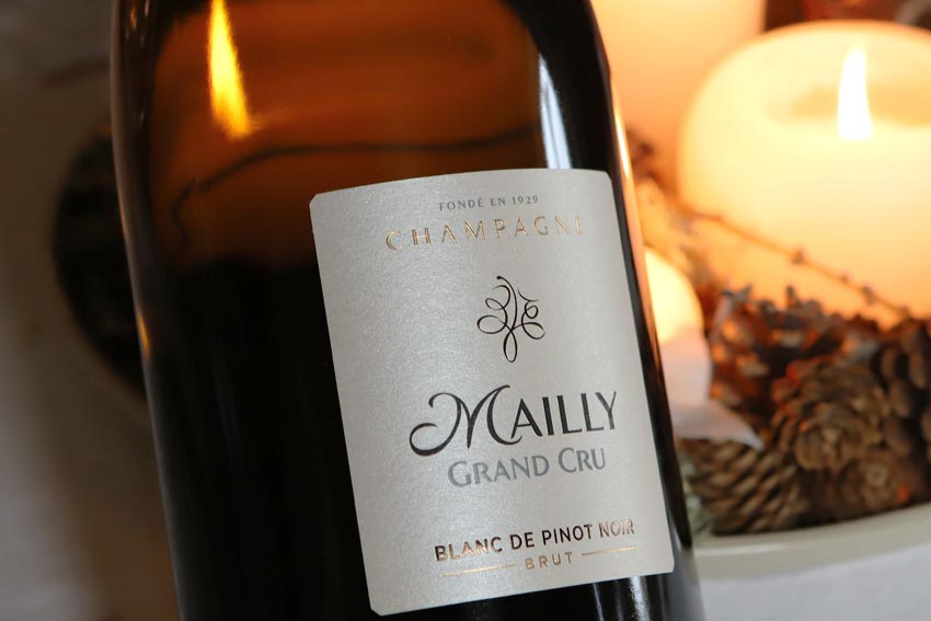 eine Flasche Champagner von Mailly dahinter strahlendes Kerzenlicht