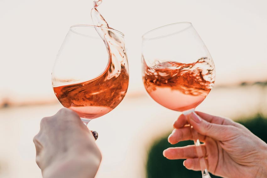 Zwei Weingläser, gefüllt mit Rosewein in schwungvoller Bewegung