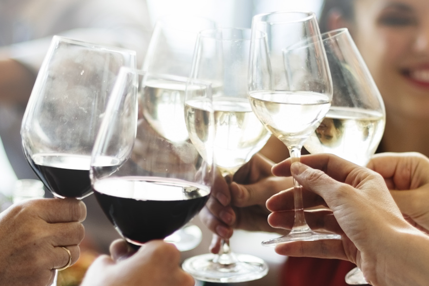 Hände mit Gläsern voller Rotwein und Weißwein, die sich zuprosten